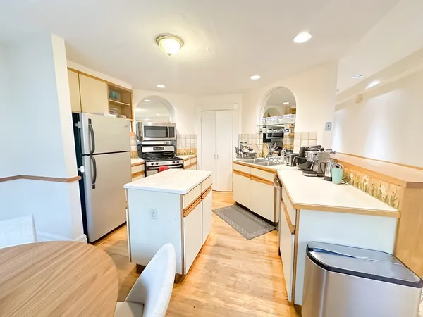 a kitchen with refrigerator a sink and a stove top oven with wooden floor