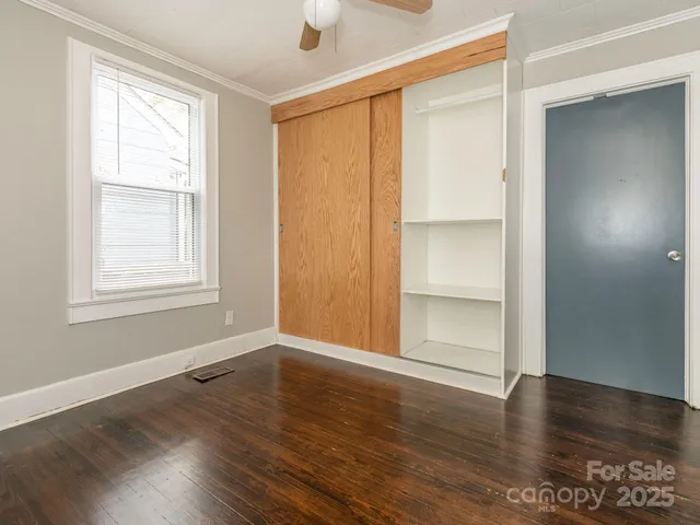 an empty room with wooden floor closet and windows