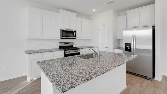 a kitchen with stainless steel appliances granite countertop a sink refrigerator and microwave