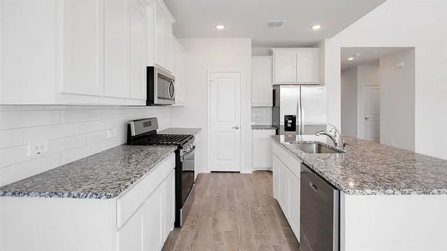a kitchen with stainless steel appliances granite countertop a sink stove and refrigerator