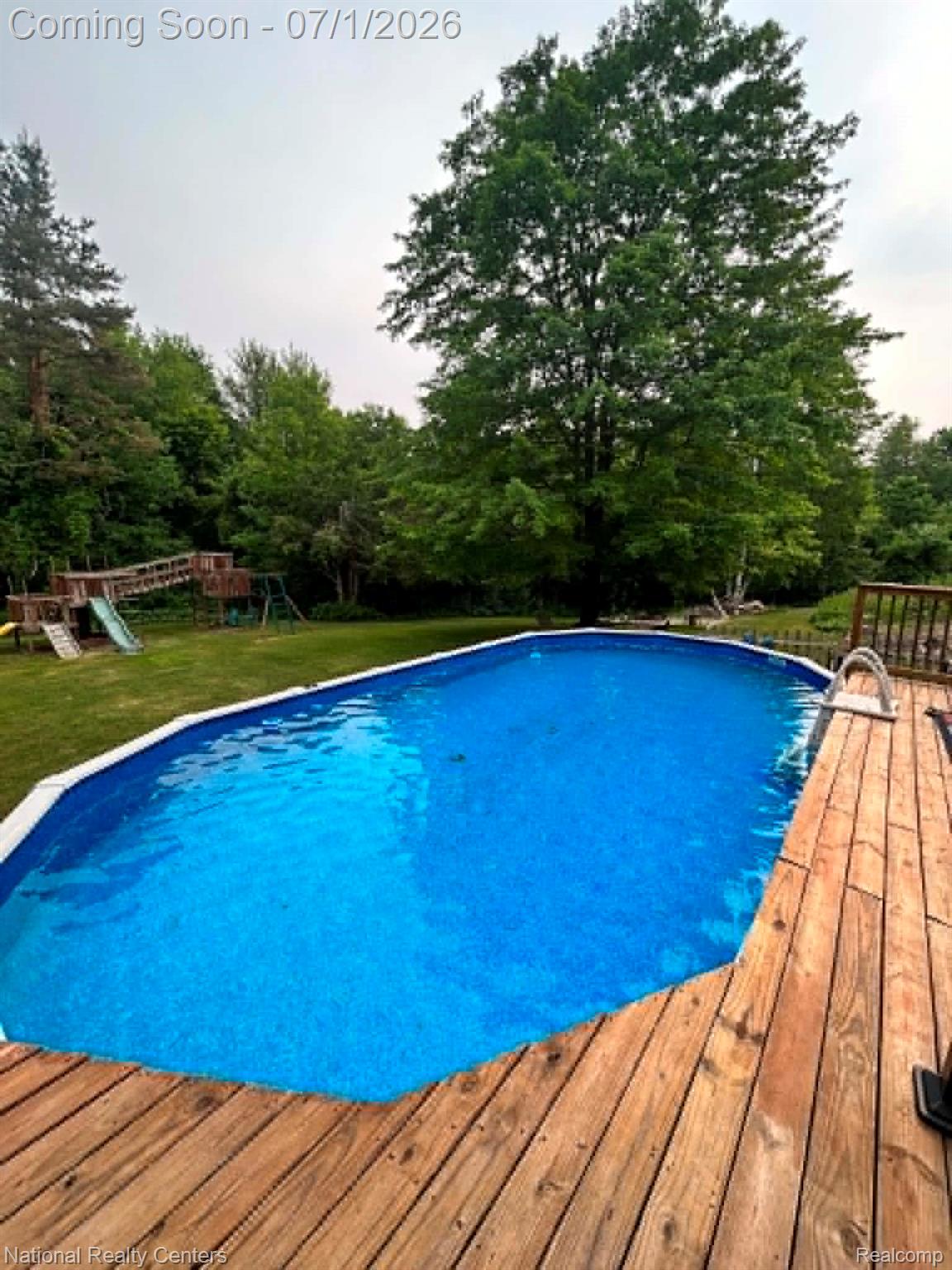 1330 Brauer Road Oxford, MI 48371 - Photo 23 of 54 Resort-style backyard featuring a pool, expansive wood deck, and surrounding mature trees