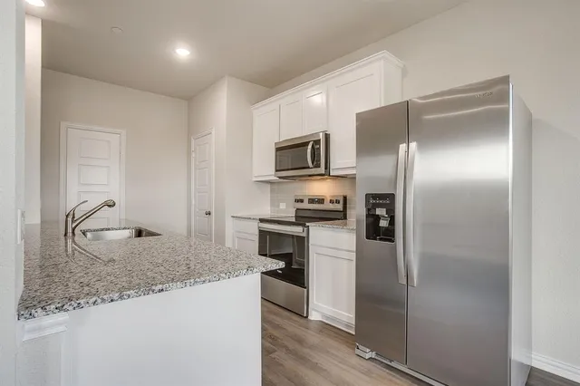 a kitchen with stainless steel appliances granite countertop a sink a stove and a wooden floors