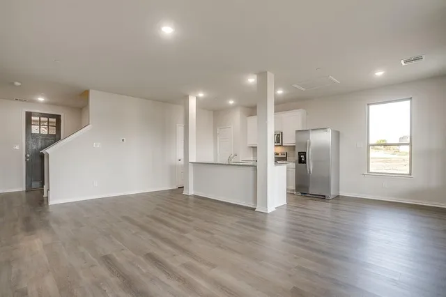 a view of an empty room with wooden floor and window