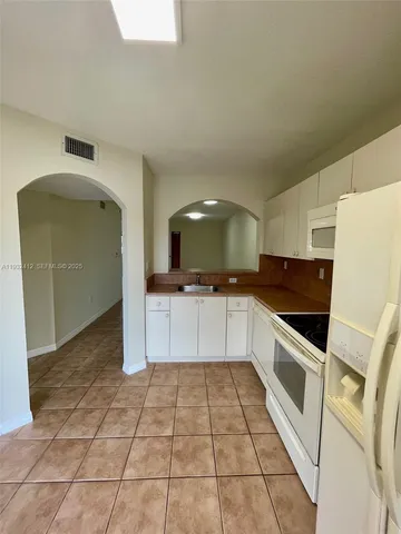 a kitchen with granite countertop a refrigerator and a stove top oven