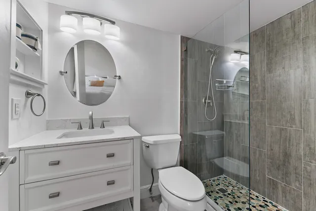 a bathroom with a toilet sink vanity granite and shower
