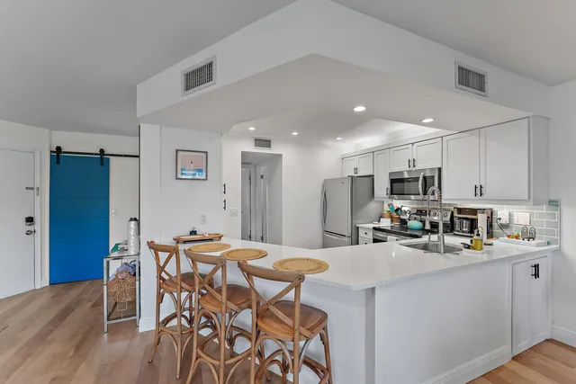 a kitchen with stainless steel appliances a dining table chairs microwave and cabinets