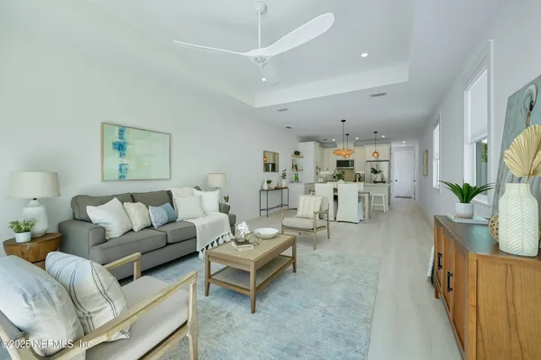 a living room with furniture potted plant and kitchen view