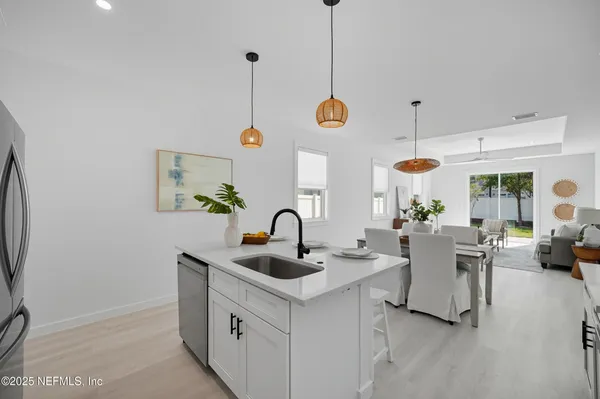 a dining room with stainless steel appliances kitchen island granite countertop a table chairs and a refrigerator