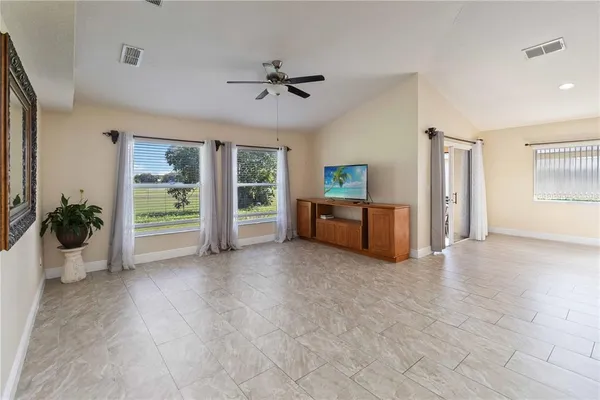 a view of an empty room and chandelier fan
