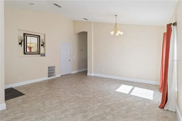 an empty room with kitchen view and windows