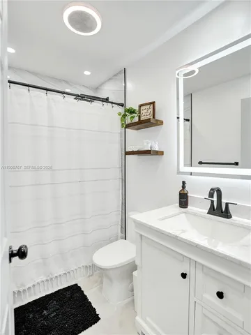 a bathroom with a sink a toilet a mirror and shower