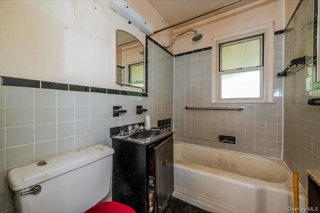 a bathroom with a sink a toilet a mirror and bathtub