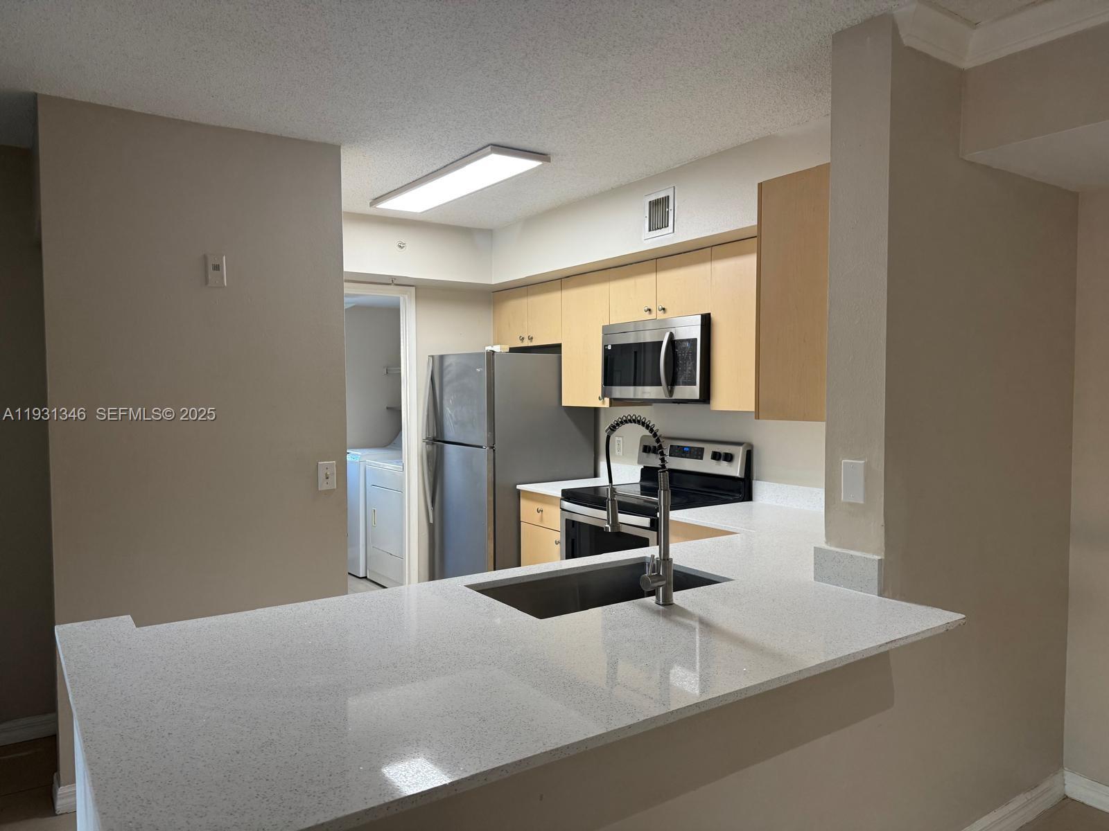 2494 Centergate Drive, Unit 201 Miramar, FL 33025 - Photo 3 of 20 a kitchen with a refrigerator a microwave a sink and a counter top space