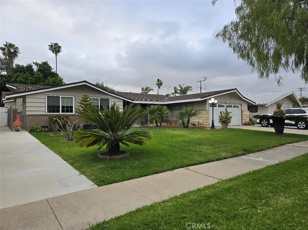 a view of house with a yard and potted plants