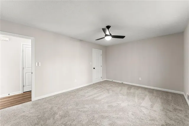 a view of an empty room with chandelier fan