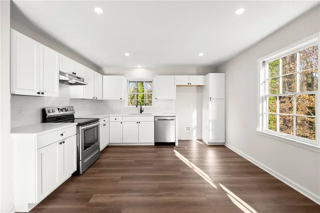 a kitchen with stainless steel appliances kitchen island wooden cabinets and a window