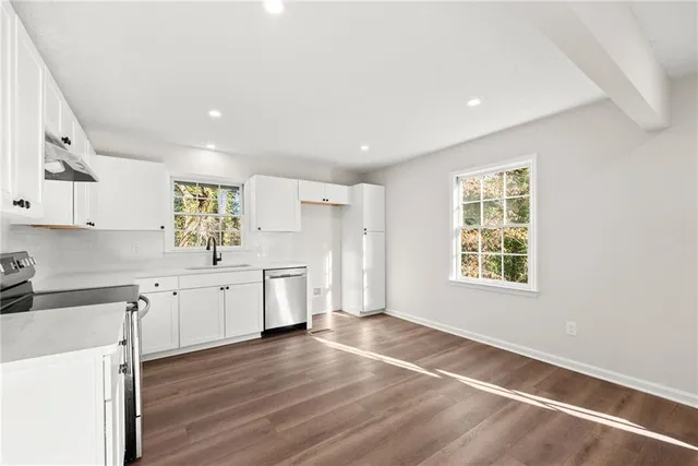 a large kitchen with a lot of counter space and wooden floor