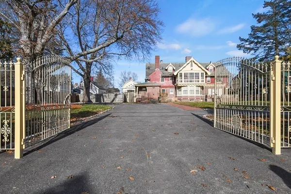 a view of a white house with a large trees next to a road