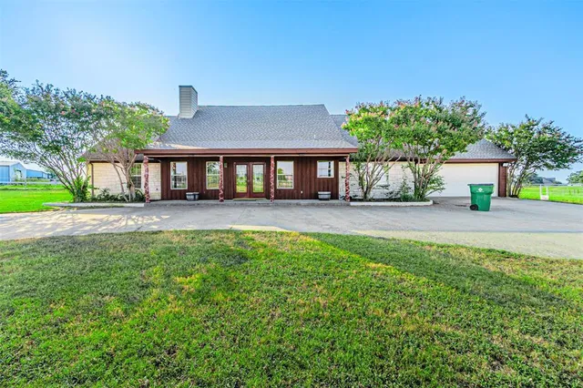 a front view of a house with a yard and palm trees