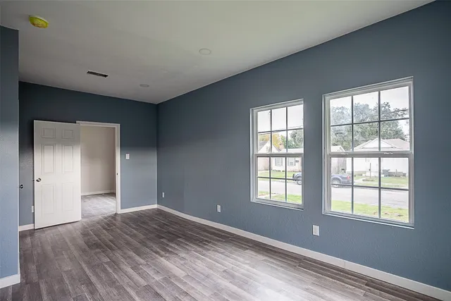 a view of an empty room with wooden floor and a window
