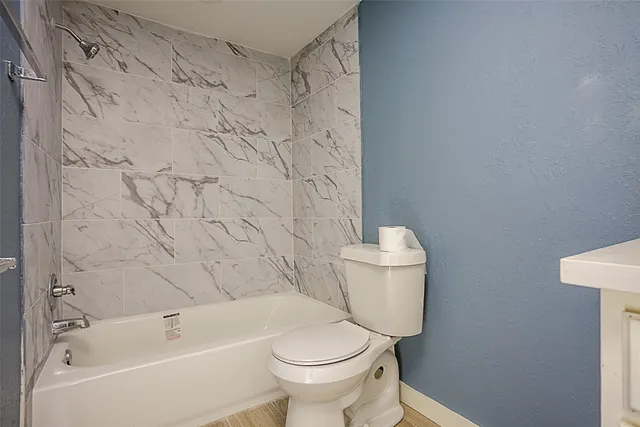 a white toilet sitting next to a bath tub and a shower curtain