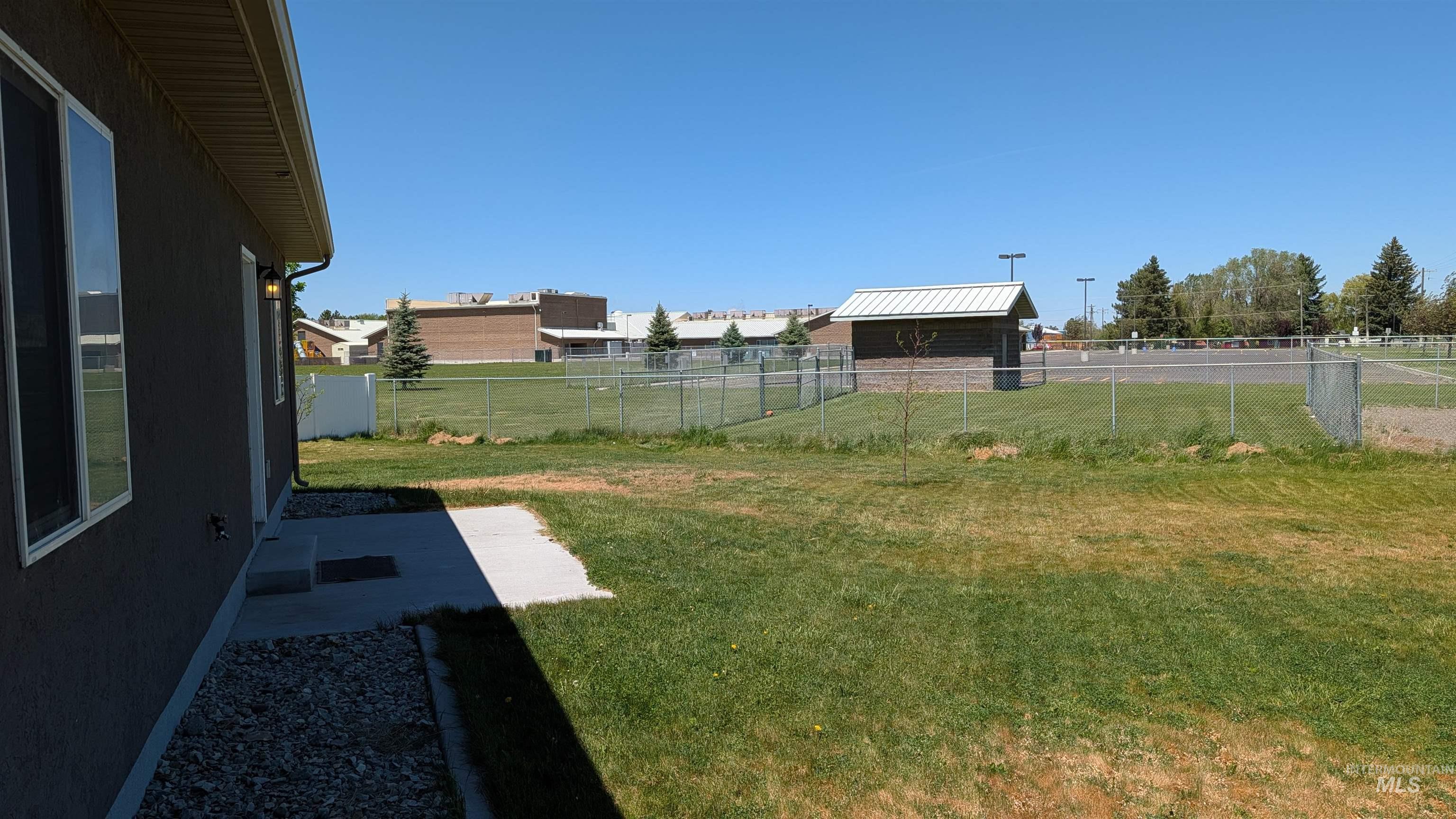 622 Lochsa Loop Heyburn, ID 83336 - Photo 7 of 17 Expansive side yard with a concrete patio, gravel border, and a chain-link fence