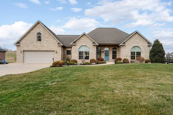 a front view of a house with a garden and trees