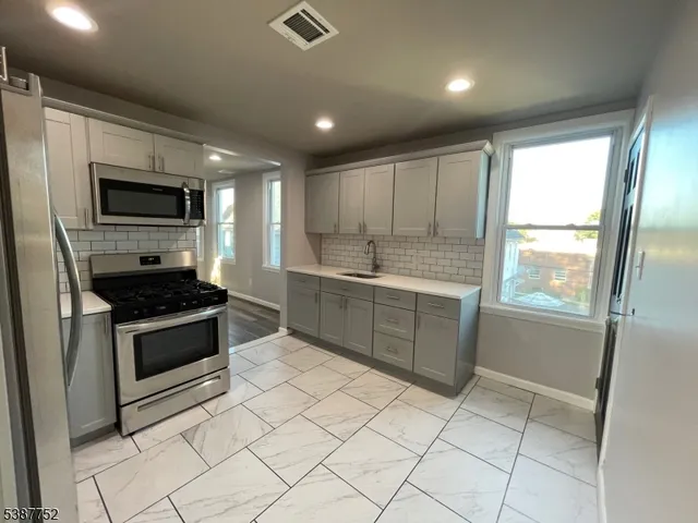 a kitchen with stainless steel appliances granite countertop a stove a sink and a refrigerator