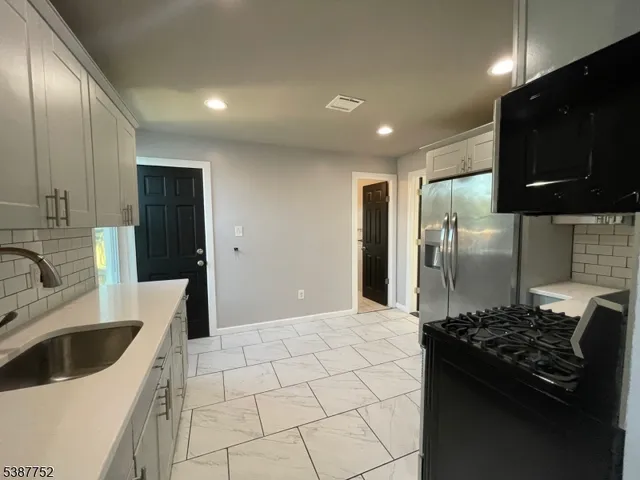 a kitchen with stainless steel appliances granite countertop a sink a stove a refrigerator and cabinets