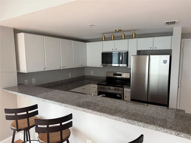 a kitchen with kitchen island a refrigerator and a stove top oven