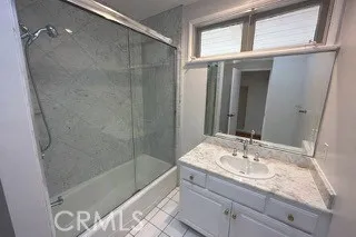 a bathroom with a granite countertop sink a mirror and shower