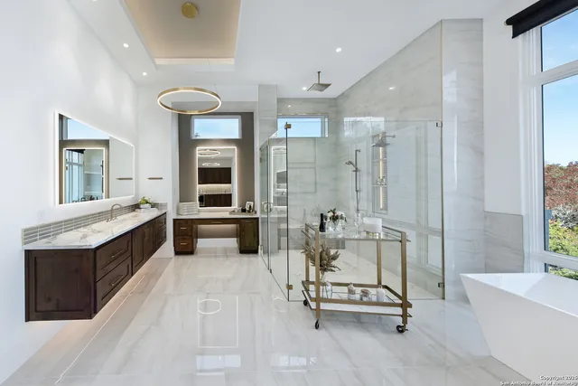 a spacious bathroom with a tub a double vanity sink a mirror and a shower