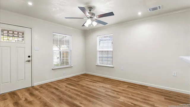 a view of an empty room with wooden floor and a window
