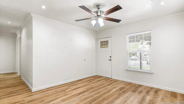 an empty room with wooden floor ceiling fan and windows
