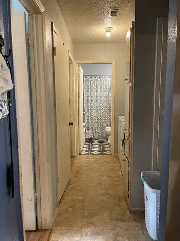 a view of a hallway with bathroom and a glass door