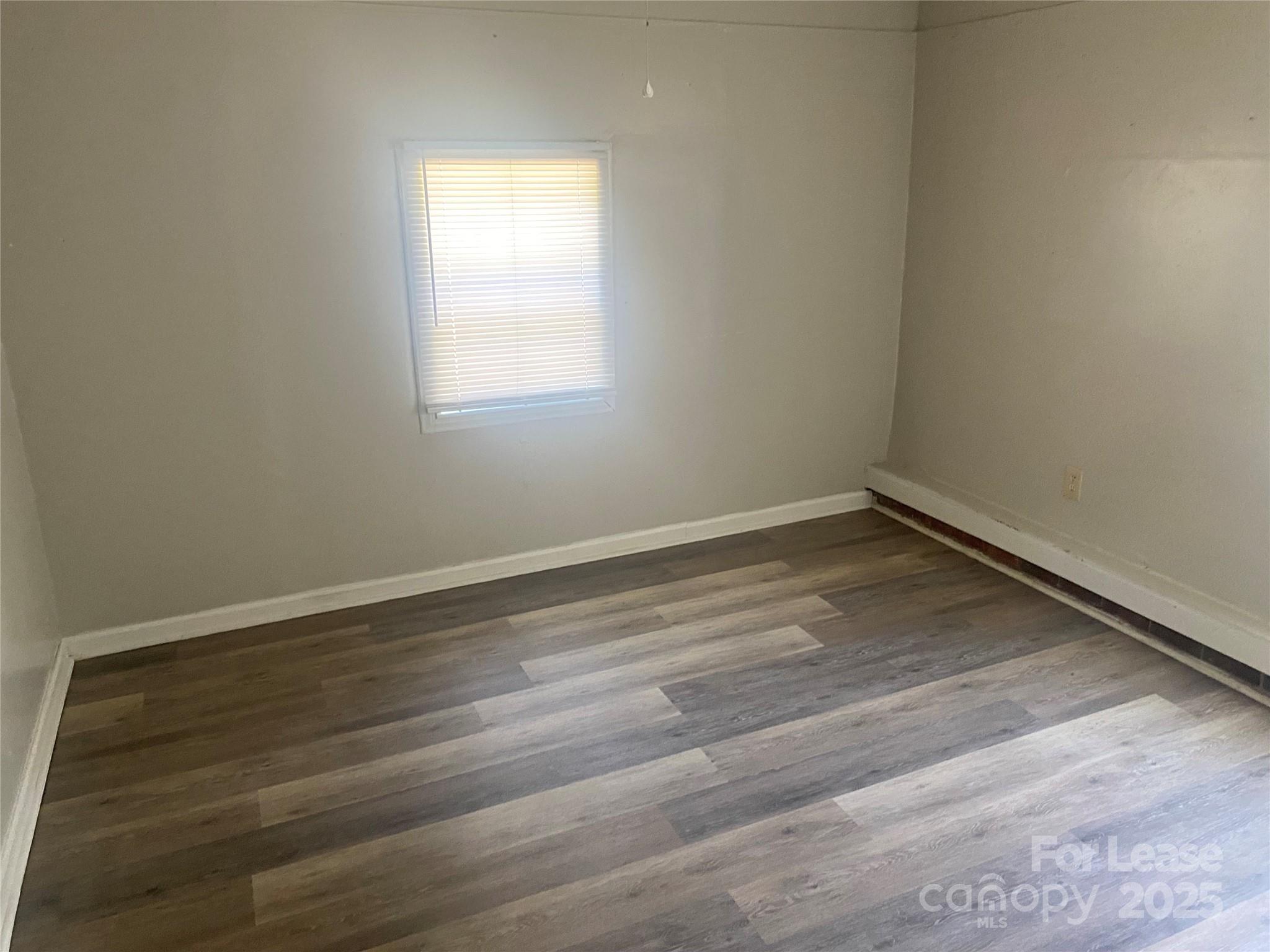 1427 Oak Hill Drive Morganton, NC 28655 - Photo 9 of 12 an empty room with wooden floor and windows