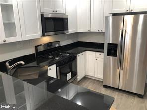 538 Newcomb Street Southeast Washington, DC 20032 - Photo 11 of 29 a kitchen with stainless steel appliances granite countertop a refrigerator a stove and a sink with wooden floor