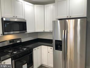 538 Newcomb Street Southeast Washington, DC 20032 - Photo 10 of 29 a kitchen with granite countertop white cabinets and black appliances