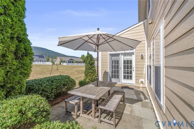 a backyard of a house with table and chairs under an umbrella
