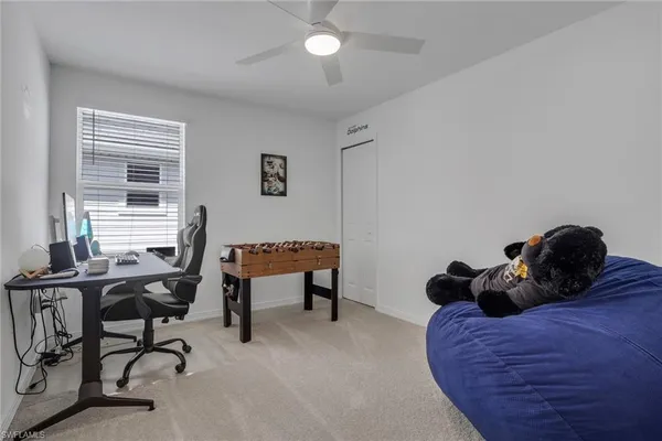 a bedroom with a bed a desk and chair with windows