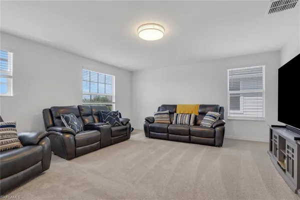 a living room with furniture a flat screen tv and a window