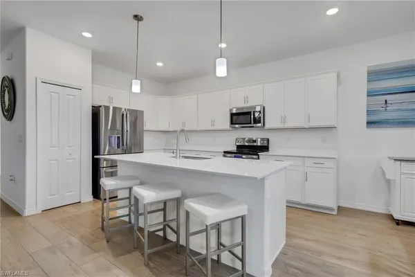 a kitchen with stainless steel appliances granite countertop a refrigerator a stove a sink a microwave and white cabinets with wooden floor