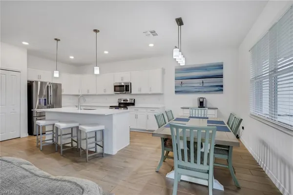 a kitchen with kitchen island granite countertop a table chairs sink and microwave