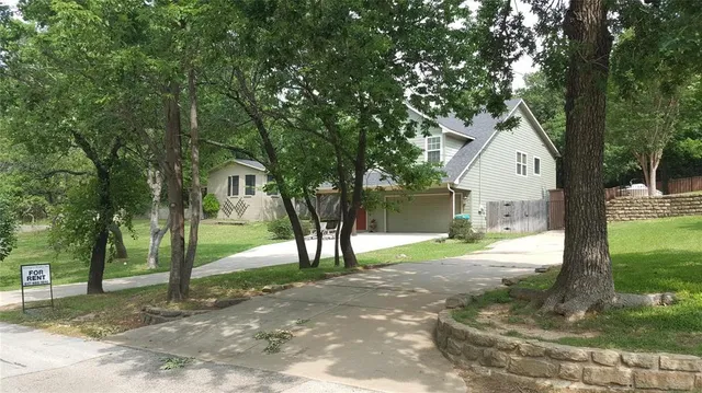 a front view of a house with a yard and tree s