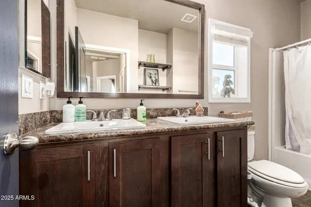 a bathroom with a granite countertop sink toilet and mirror