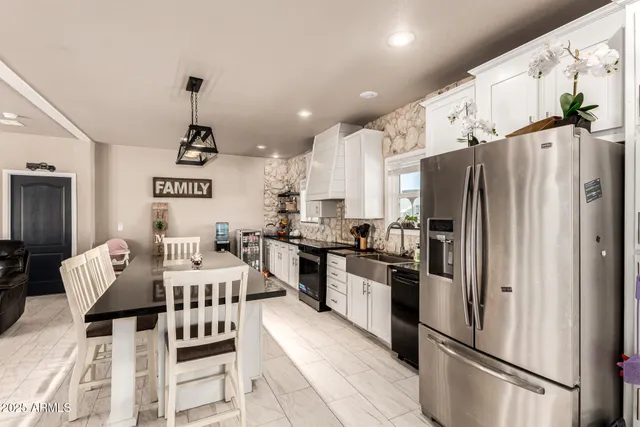 a kitchen with stainless steel appliances granite countertop a refrigerator a stove a sink a dining table and chairs with wooden floor