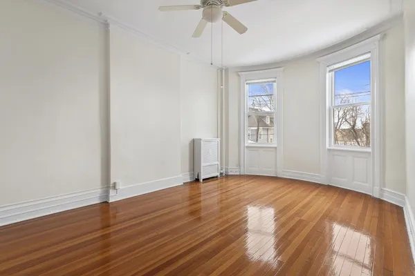 a view of empty room with wooden floor and fan