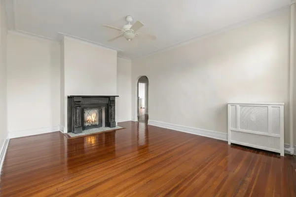 an empty room with wooden floor fireplace and staircase