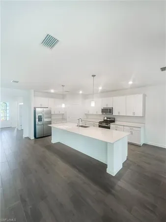 a view of kitchen with kitchen island a sink dishwasher and a stove with wooden floor