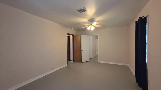 an empty room with a ceiling fan and window
